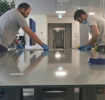 Mitarbeiter von Delta Werbetechnik machen Smartfilm auf eine Glasscheibe in Köln